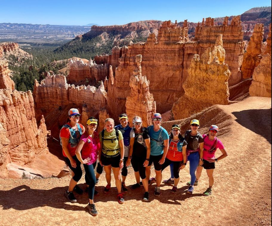A group on a running tour pose in front of the rock structures at Bryce Canyon